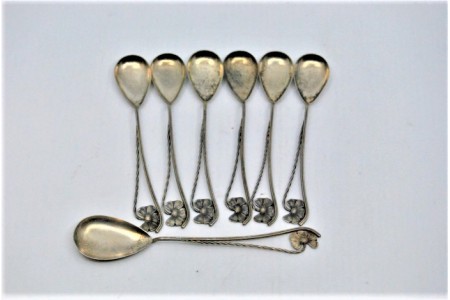 Conjunto de seis colheres de café e pá de açúcar em prata com conchas douradas e cabos vazados com motivos florais.